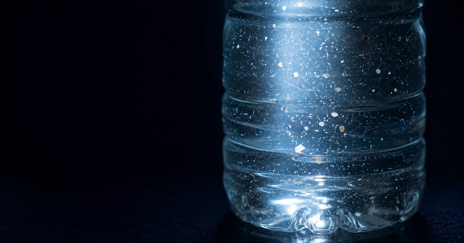 Detalle macro de agua dentro de una botella plástica con partículas suspendidas visibles a contraluz
